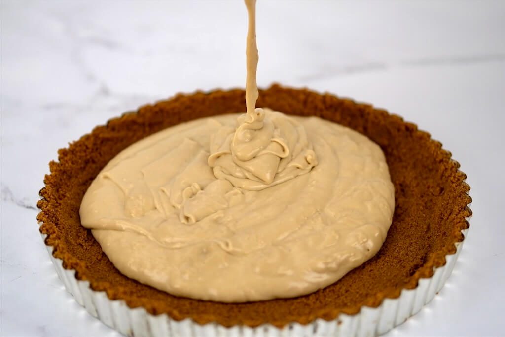 cooled filling being poured onto a prepared gingersnap crust for Butterscotch Pie