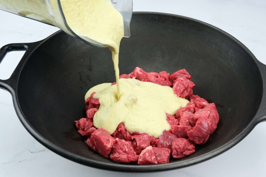 blended ingredients mixed with raw beef for the dish Indonesian beef rendang