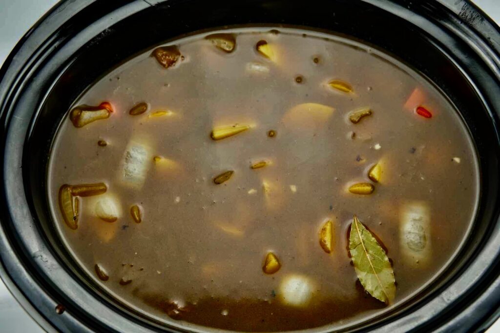 seared beef and vegetables with wine and beef stock in a slow cooker