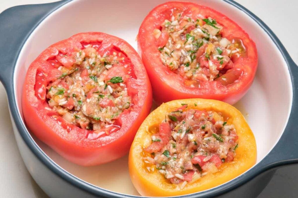 tomatoes filled with sausage rice mixture with tomato pulp, rice, herb, and other aromatics