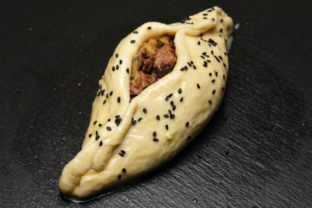 shamburak dough with potato and beef filling brushed with egg wash and sprinkled with nigella seeds